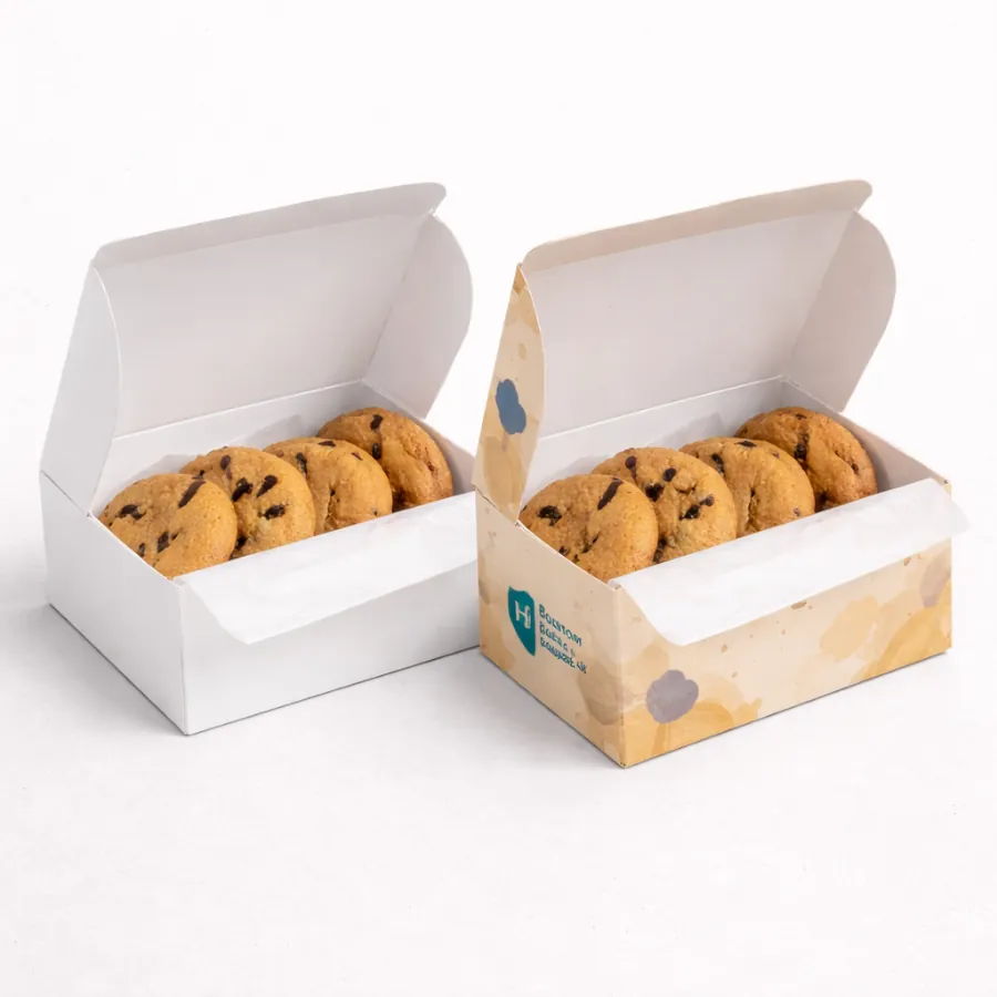Two open biscuit boxes with hinged lids- each containing a row of chocolate chip biscuits- class=